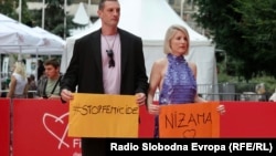 Muzičarka Ida Prester na crvenom tepihu SFF-a s imenom ubijene žene u Gradačcu. Njen suprug Vani Peševski drži natpis "Stop femicidu", Sarajevo, 15. august 2023. 