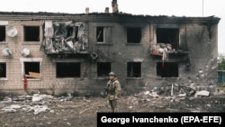 Українській поліцейський оглядає зруйновані будівлі у Вовчанську