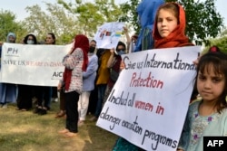 Afghans hold placards as they gather to demand help from the UN for asylum abroad in Islamabad on May 12, 2022.