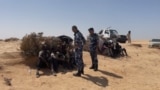 Libyan border guards talk to migrants in the desert near Libyan-Tunisian border