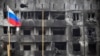 Российский флаг на фоне выгоревшего – в результате бомбардировок и обстрелов русской армии – жилого дома Мариуполя. 11 апреля 2022 года