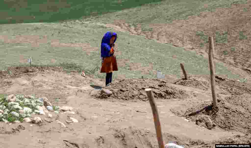 A young girl, who lost four of her family members in a flash flood in northern Afghanistan, stands beside the grave of her brother near the village of Sherjalal.