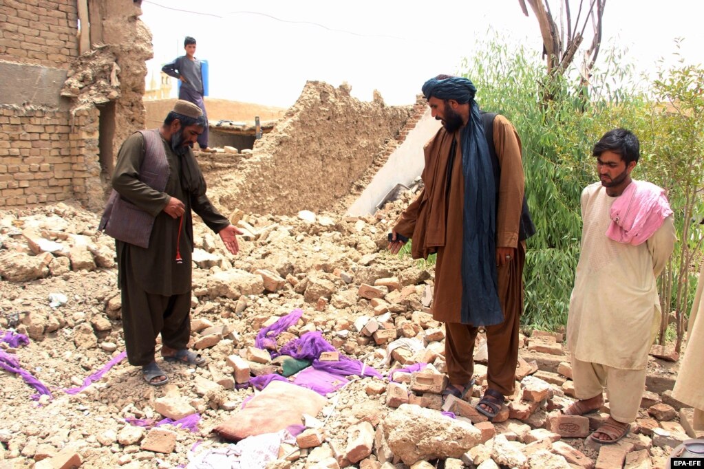 Persone in piedi tra le macerie di un edificio crollato a Kandahar il 22 luglio.  