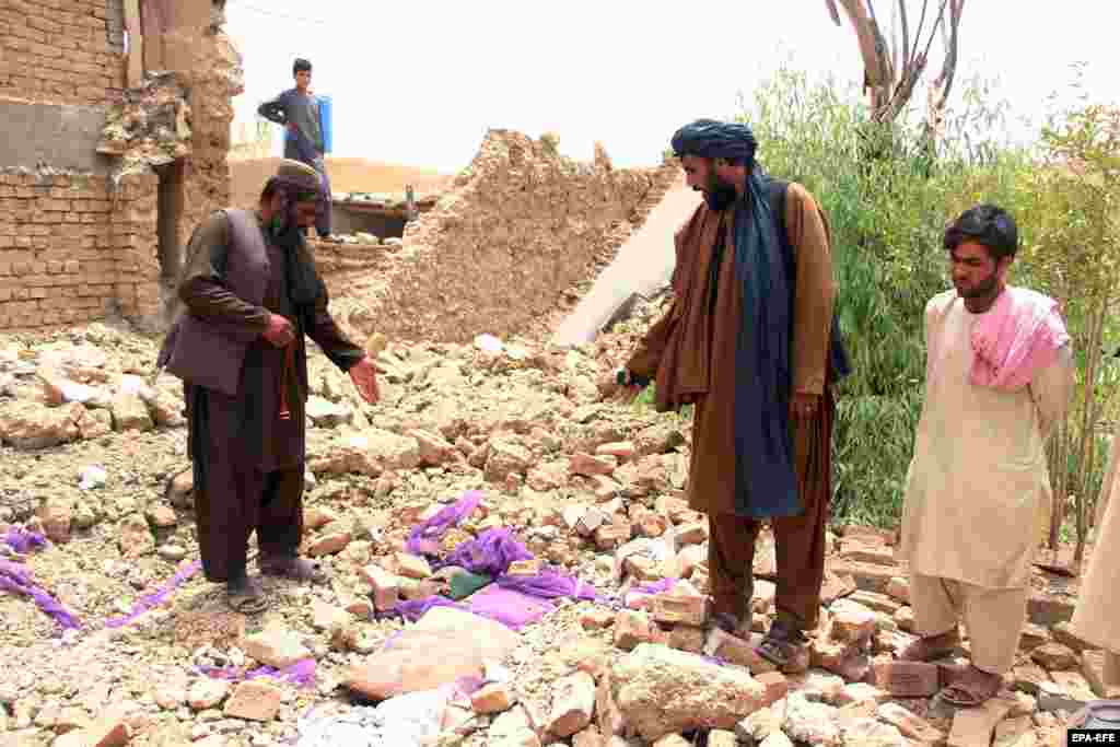People stand in the rubble of a collapsed building in Kandahar on July 22. &nbsp;