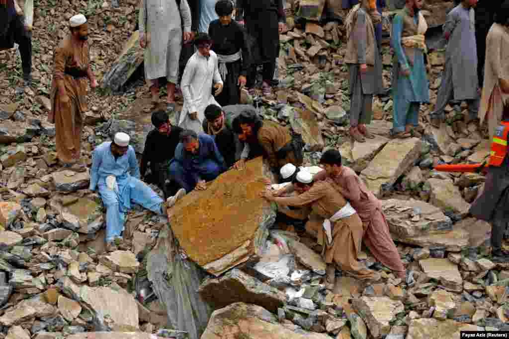 People remove a rock slab as they continue to search for survivors. The Torkham border crossing -- a vital commercial artery and a trade route for Pakistan to Central Asian countries -- was recently closed by the Afghan Taliban after Islamabad accused Kabul of providing a safe haven for Pakistani Taliban militants.