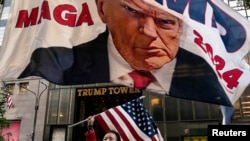 Поддржувач на поранешниот американски претседател Доналд Трамп држи американско знаме пред кулата Трамп во Њујорк, САД на 1 октомври 2023 година