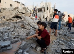 Палестинські діти сидять на уламках будинку, знищеного ударом Ізраїлю. Сектор Гази, 17 жовтня 2023 року