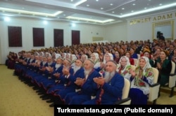 Elderly men and women – dressed in matching traditional clothing – attend an official gathering. (file photo)