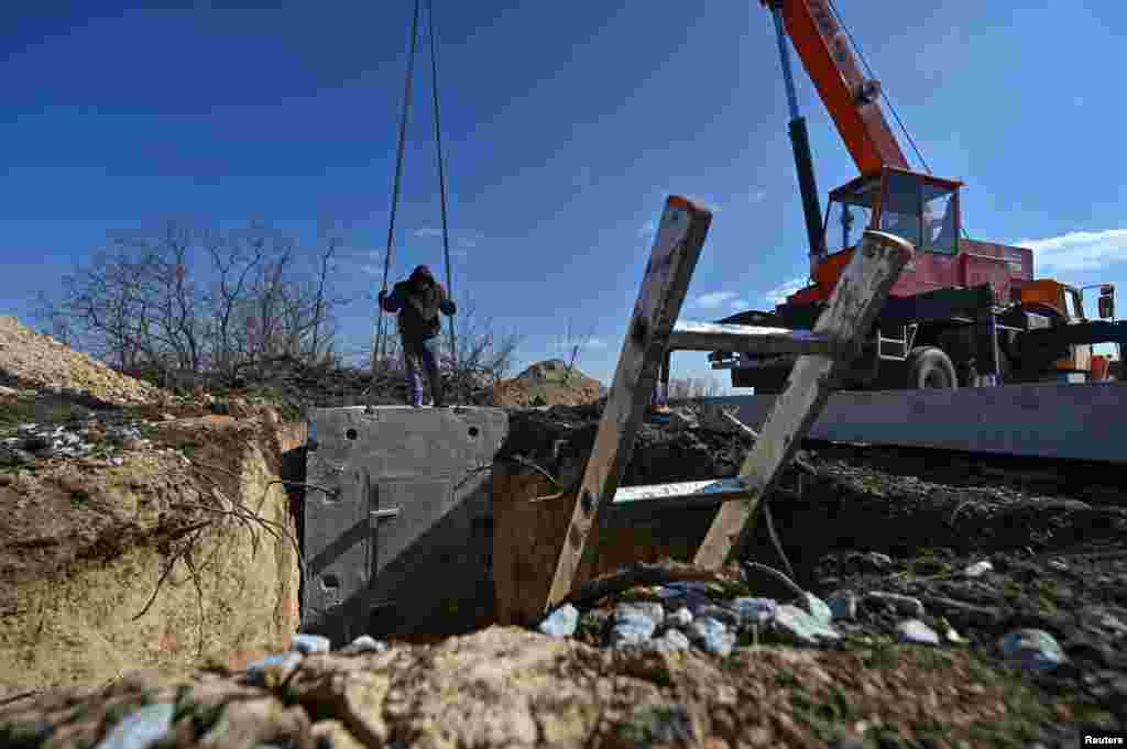 Рабочие устанавливают часть массивного бетонного сооружения. Премьер-министр Денис Шмыгаль в январе сообщил, что Киев выделил на строительство укреплений 466 миллионов долларов, назвав это &laquo;рекордной суммой&raquo;