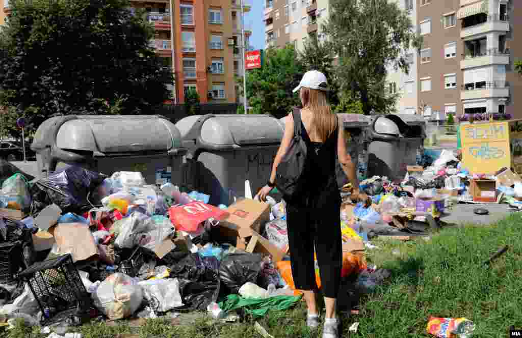 Жителка на Скопје ги гледа купиштата ќеси со отпад во една од скопските градски населби.