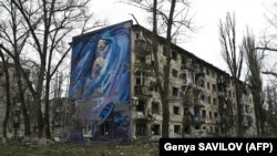 Мурал із зображенням жінки з дитиною на стіні пошкодженого внаслідок обстрілів армією РФ будинку в Авдіївці, 4 квітня 2023 року