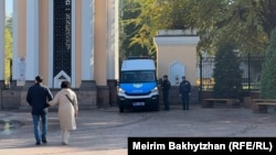 Полицейские и микроавтобус с проблесковыми маячками у входа в Центральный парк в Алматы. 25 октября 2023 года