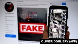 Në ekranin e telefonit shihet një ndërtesë e shkatërruar në Ukrainë, si pasojë e sulmit rus, ndërsa në monitorin e kompjuterit, një faqe online që përhap lajme të rreme.