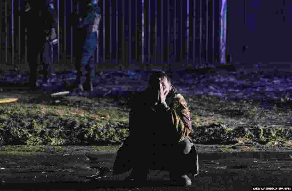 A man kneels by the site of a drone attack in Kharkiv, Ukraine.