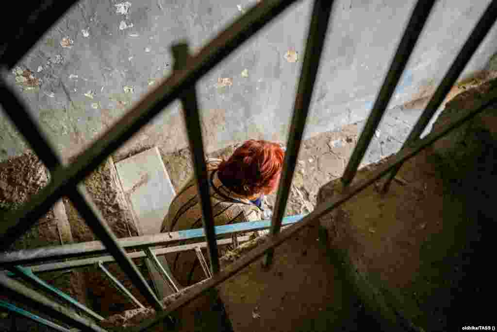 Женщина сидит на лестнице жилого дома, разрушенного в результате удара по Степанакерту