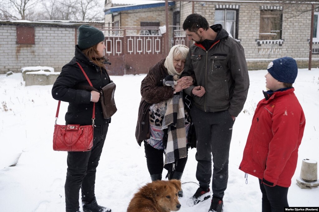 As his wife Iryna (left) and his son Oleksandr (right) look on, Serhiy Akusov helps his ill 75-year-old mother-in-law, Rayisa, evacuate from her family home. Moments later she passed away.  