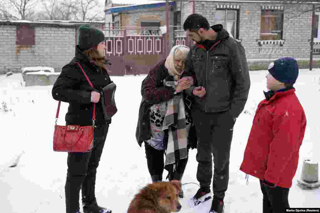 Сергей Акусов вместе со своей женой Ириной (слева) и сыном Александром (справа) помогает пожилой и больной 75-летней тёще Раисе эвакуироваться из её дома. Через некоторое время она скончалась&nbsp;