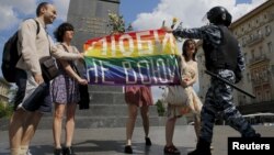 Participanții țin un steag curcubeu în timp ce un polițist îi oprește în timpul unui miting al comunității LGBT în centrul Moscovei, Rusia, 30 mai 2015. 