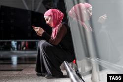 A woman wearing a head scarf waits at Vnukovo International Airport in Moscow.