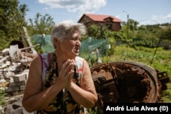 Tamara Evdokimova își cultivă grădina în ciuda turelei tancului blocat în curtea ei. „Nu mai vreau să locuiesc în casa asta de nebuni”, spune ea.