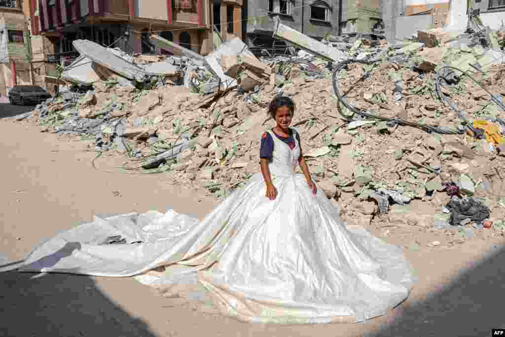 Palestinska djevojka pozira s vjenčanicom pronađenom među ruševinama zgrada uništenih tokom izraelskog bombardiranja, u Khan Yunisu na jugu Pojasa Gaze, 20. juna, dok se nastavlja sukob na palestinskom teritoriju između Izraela i Hamasa.