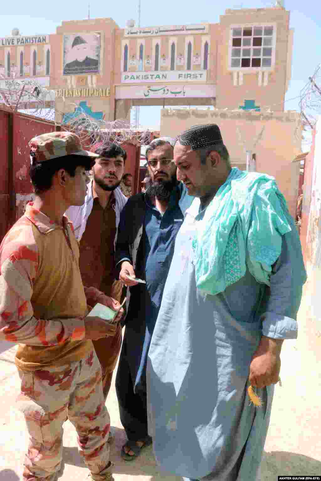 A soldier checks documents of people crossing into Pakistan. &nbsp;