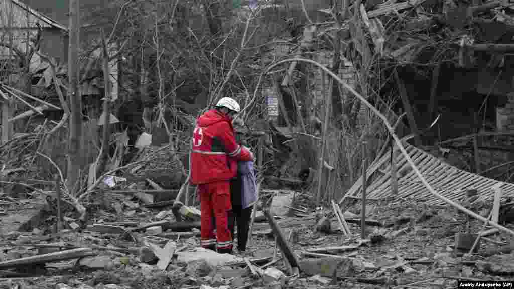 A medical worker comforts a woman amid the rubble.