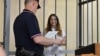 Aleksandra Skochilenko appears in the defendant's cage during her trial in St. Petersburg.