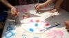 Fëmijët duke pikturuar mbi një pëlhurë gjatë aktiviteteve në qendrën e The Ideas Partnership për Ditën Ndërkombëtare të Fëmijëve.