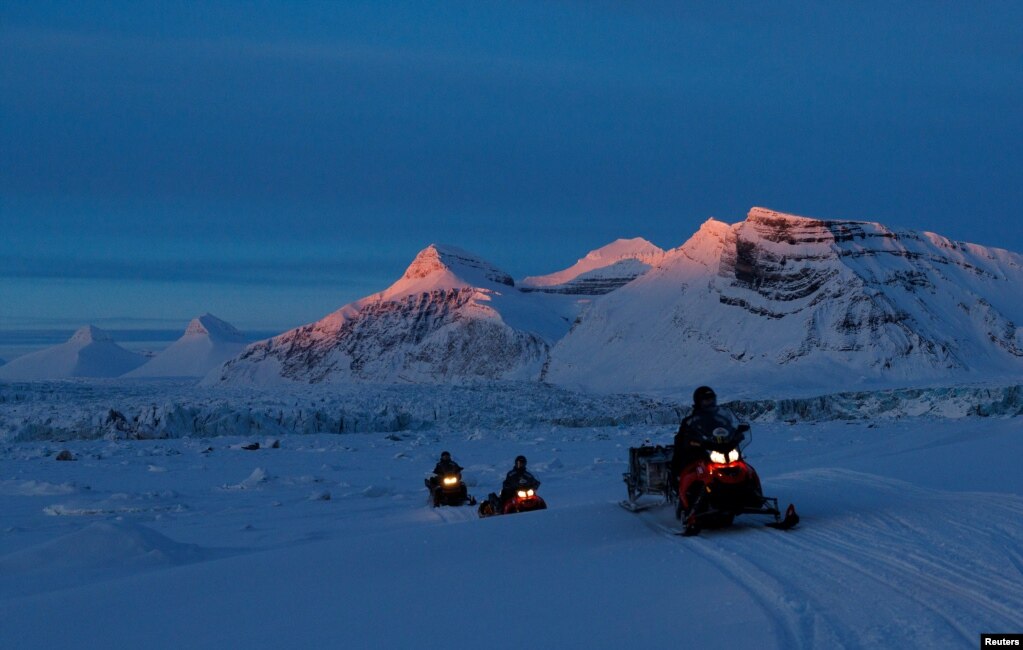 Shkencëtarët e Institutit Polar Norvegjez (NPI) duke ngarë makinat e tyre ndërsa dielli perëndon në brigjet e Kongsfjordit dhe akullnajës Kronebreen pranë Ny-Aalesundit, Svalbard, Norvegji, 10 prill 2023.
