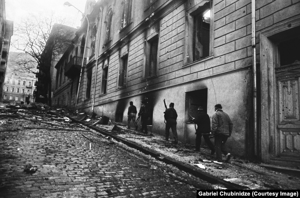 Persona të armatosur në Tbilisi në 1991 duke kaluar pranë vendit ku Shasha Selipanov kishte jetuar kur ishte fëmijë.