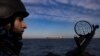 Военнослужещ от бреговата охрана на Украйна наблюдава от патрулна лодка, докато товарен кораб плава в Черно море, 7 февруари 2024 г.