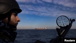 Военнослужещ от бреговата охрана на Украйна наблюдава от патрулна лодка, докато товарен кораб плава в Черно море, 7 февруари 2024 г.