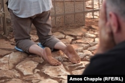 A pilgrim who walked barefoot to Apparition Hill prays in front of the statue of Mary.