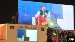 Imran Khan (bottom left) speaks to supporters from behind a bulletproof shield at a rally in Lahore early on March 25. 