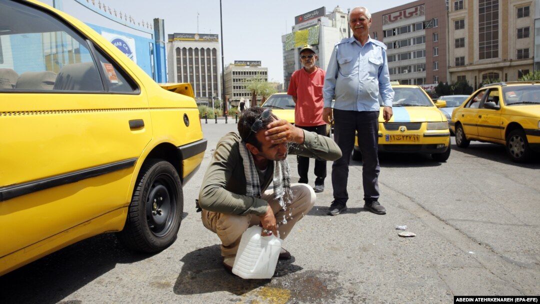 A taxi driver splashes water on his face to cool off in downtown Tehran.