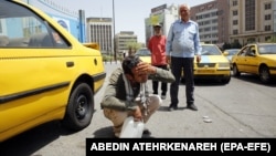 A taxi driver splashes water on his face to cool off in downtown Tehran.