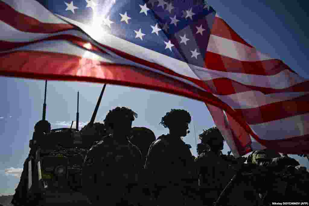 U.S. Army soldiers stand in formation next to a U.S. flag and a U.S. Army armored vehicle as they take part in the NATO Noble Blueprint 23 joint military exercise at the Novo Selo military ground in northwestern Bulgaria.