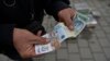 Ulični prodavac drži dinare u Gračanici u centralnom delu Kosova, 1. mart 2024.