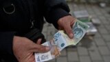 Ulični prodavac pokazuje srpske dinare u Gračanici, gradu u centralnom Kosovu, 1. marta 2024.