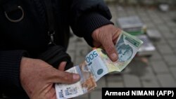 Ulični prodavac pokazuje srpske dinare u Gračanici, gradu u centralnom Kosovu, 1. marta 2024.