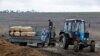 Рабочие едут в кузове трактора с гробами на кладбище в поселке Старый Крым под Мариуполем, контролируемом Россией. 4 февраля 2023 года.