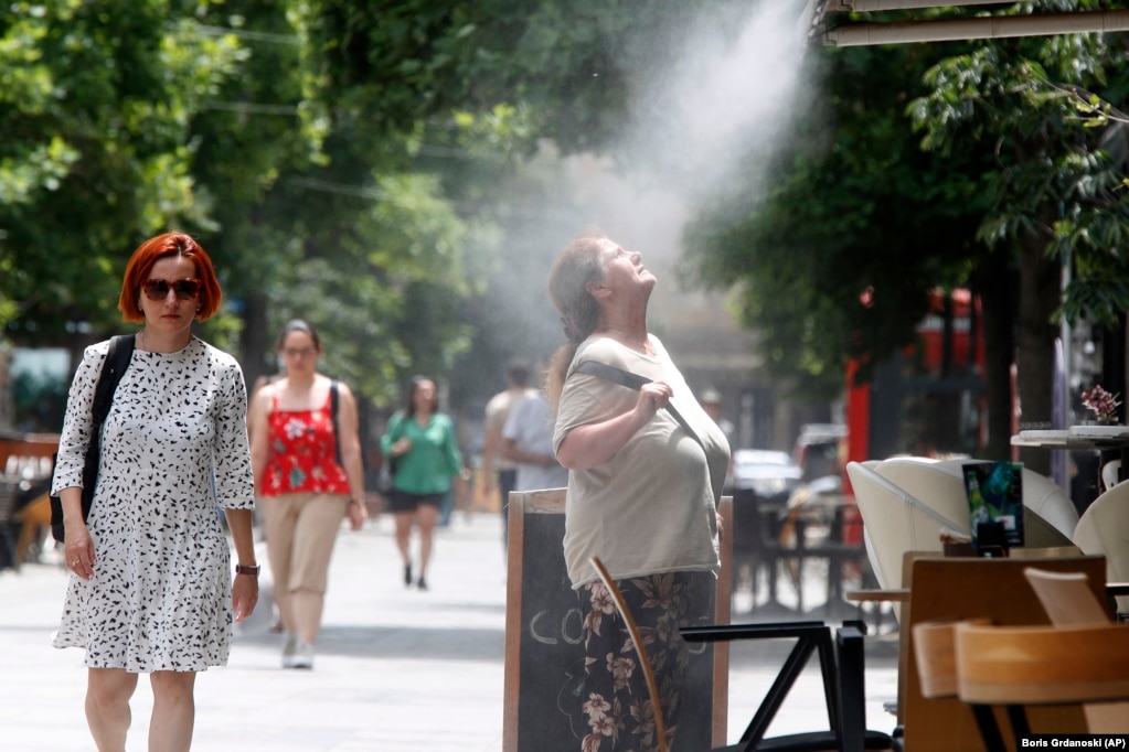 Një grua përpiqet të freskohet me mjegull uji në Shkup, ku temperaturat pritet të arrijnë deri në 37 gradë celsius më 22 qershor. &nbsp;