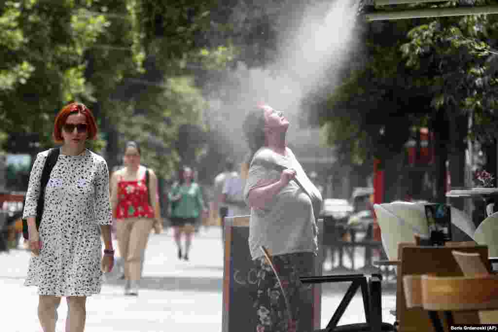 Žena pokušava da se rashladi vodenom maglom u Skoplju, gdje se mjeri i do 37 stepeni Celzijusa 22. juna. &nbsp;
