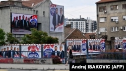 Žena prolazi pored predizbornih bilborda na kojima su predstavljeni predsednik Srbije Aleksandar Vučić i drugi funkcioneri Srpske napredne stranke (SNS) u Beogradu 31. maja 2024, pre glasanja na lokalnim izborima.