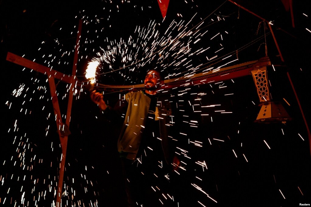 Një burrë tund një fishekzjarre të bërë vetë ndërsa palestinezët e zhvendosur zbukurojnë tendat e tyre për Ramazan në Rafah, Rripi i Gazës, mars 2024.