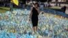 A woman visits a makeshift memorial place with Ukrainian flags with the names of fallen service members on Kyiv's Independence Square.