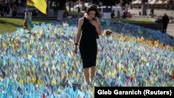 A woman visits a makeshift memorial place with Ukrainian flags with the names of fallen service members on Kyiv's Independence Square.