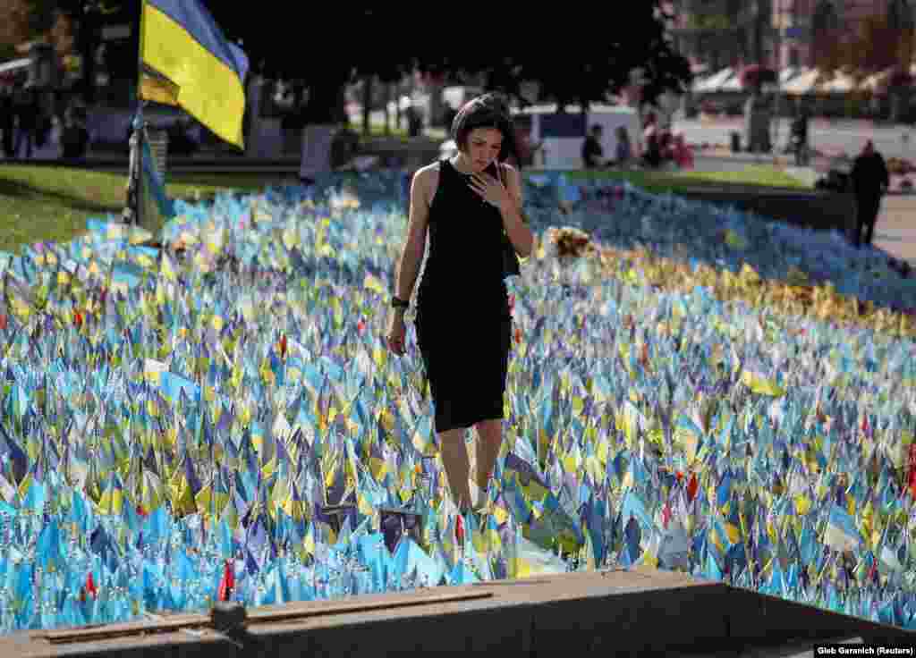 Женщина у импровизированного мемориала с флагами, на которых нанесены имена погибших воинов. Майдан Незалежности в Киеве, 26 сентября. &laquo;Это чей-то муж, чей-то сын, чей-то отец, &mdash; говорит&nbsp;Ябченко. &mdash; Это украинец. Мне будет больно, если, не дай бог, его убьют&raquo;&nbsp;