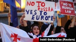  Жени държат плакати с надписи 